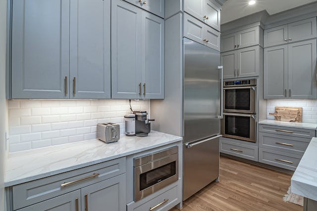 kitchen with light blue cabinets, white counters and stainless steel appliances